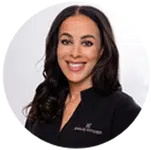 Eine lächelnde Frau mit dunklen Haaren in schwarzer Kleidung.