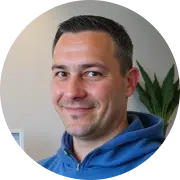 Mann mit blauem Kapuzenpullover lächelt vor einer Pflanze