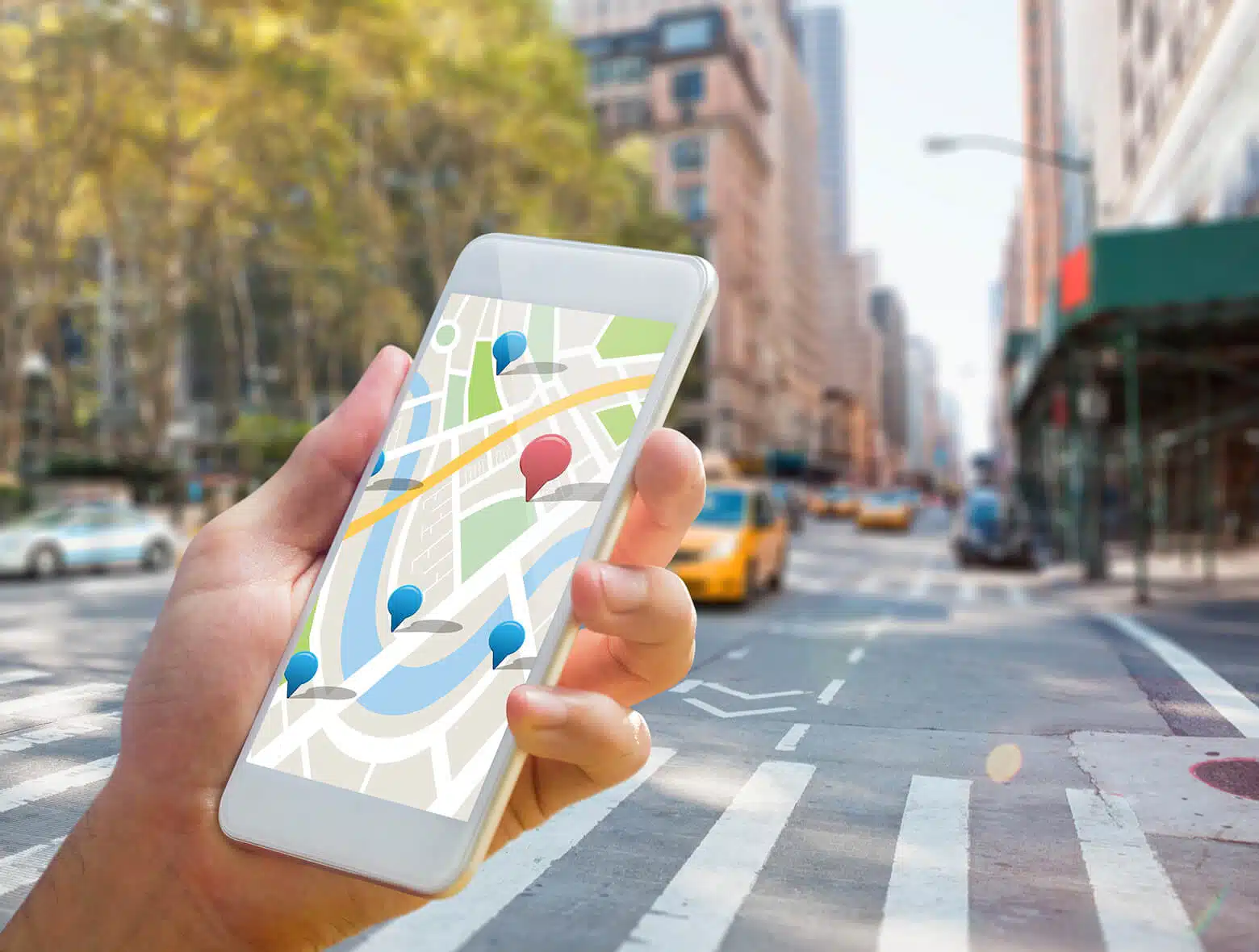 Person hält Smartphone mit digitaler Karte in urbaner Umgebung.